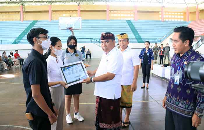 Bupati Jembrana I Nengah Tamba menyerahkan secara simbolis dana penghargaan pendidikan, Selasa (20/12/2022). Foto: Menitini/M-011)