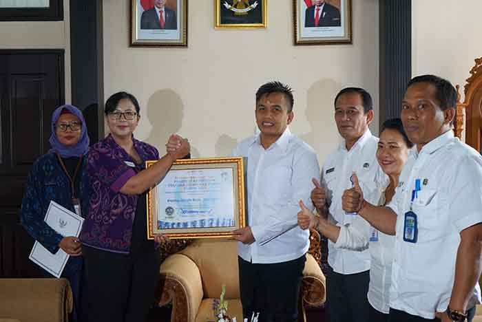 Sertifikat predikat kepatuhan diserahkan oleh Kepala perwakilan Ombudsman RI Provinsi Bali, Ni Nyoman Sri Widhiyanti kepada Wakil Bupati Jembrana di ruang VIP kantor Bupati Jembrana, Rabu (1/2/2023). (Foto: Humas)