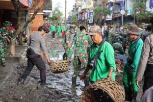 Personel TNI AD bersama relawan dan aparat kepolisian bergotong royong membersihkan lumpur pascabanjir di salah satu kawasan terdampak di Bali.