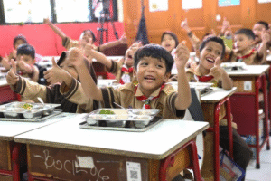 Anak-anak sekolah dasar menikmati santapan bergizi dalam suasana ceria di ruang kelas. Kementerian Kesehatan menekankan pentingnya keamanan pangan dalam Program Makan Bergizi Gratis agar makanan yang disajikan aman dan berkualitas bagi peserta didik.