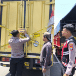 Petugas Polresta Banyuwangi saat memasang garis polisi dan label barang bukti pada truk box bermuatan ribuan botol arak ilegal yang diamankan di kawasan Kalipuro.