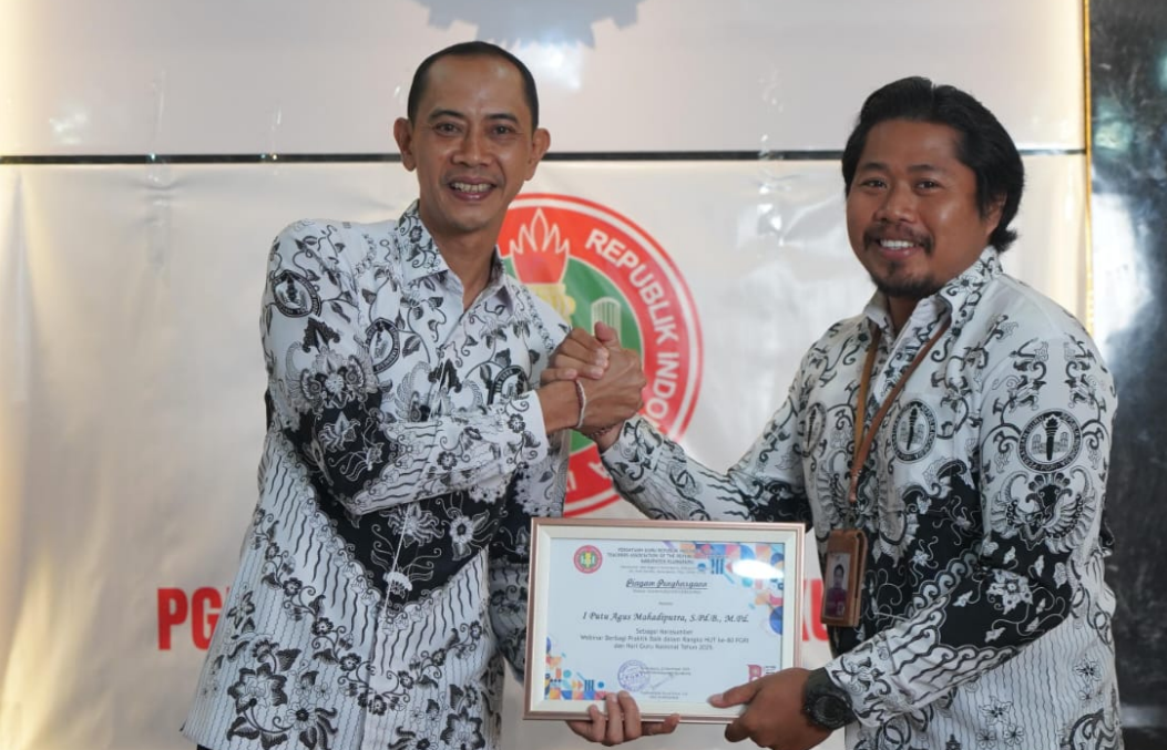 Wakil Bupati Klungkung sekaligus Ketua PGRI Klungkung, Tjokorda Gde Surya Putra, menyerahkan piagam penghargaan kepada salah satu guru berprestasi pada peringatan HUT ke-80 PGRI di SMAN 2 Semarapura.