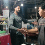 Turis asal Somalia berjabat tangan dengan sopir taksi online usai menyelesaikan kesalahpahaman terkait dugaan pencurian ponsel, disaksikan petugas Polsek Denpasar Timur, Senin (4/11/2025) malam.