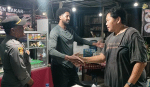 Turis asal Somalia berjabat tangan dengan sopir taksi online usai menyelesaikan kesalahpahaman terkait dugaan pencurian ponsel, disaksikan petugas Polsek Denpasar Timur, Senin (4/11/2025) malam.