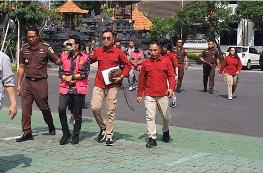 Petugas Kejaksaan Tinggi Bali mengawal dua tersangka kasus dugaan korupsi penyaluran rumah subsidi saat digiring menuju mobil tahanan usai penetapan dan penahanan di Kantor Kejati Bali, Rabu (17/12).