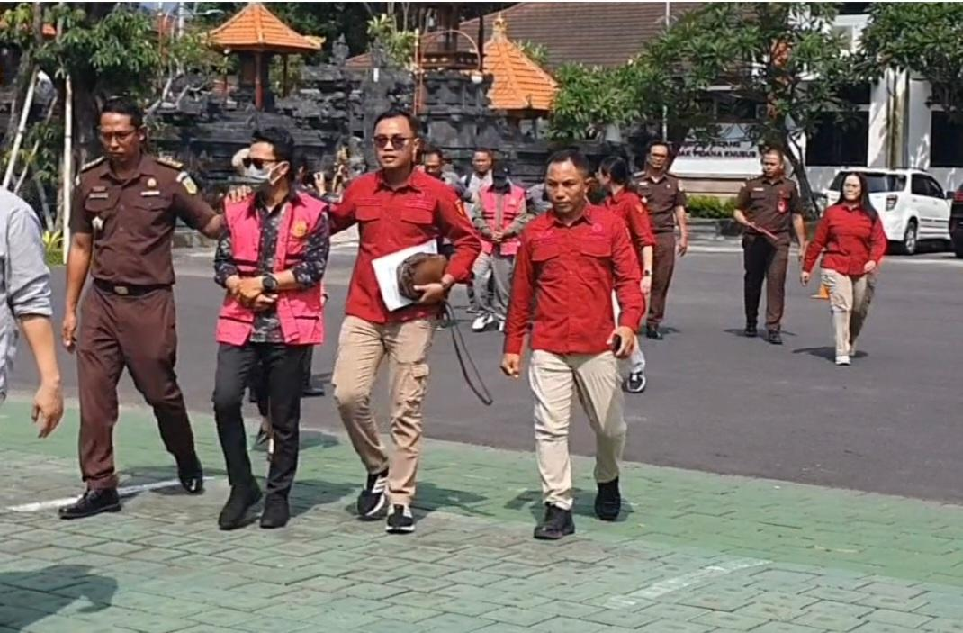 Petugas Kejaksaan Tinggi Bali mengawal dua tersangka kasus dugaan korupsi penyaluran rumah subsidi saat digiring menuju mobil tahanan usai penetapan dan penahanan di Kantor Kejati Bali, Rabu (17/12).