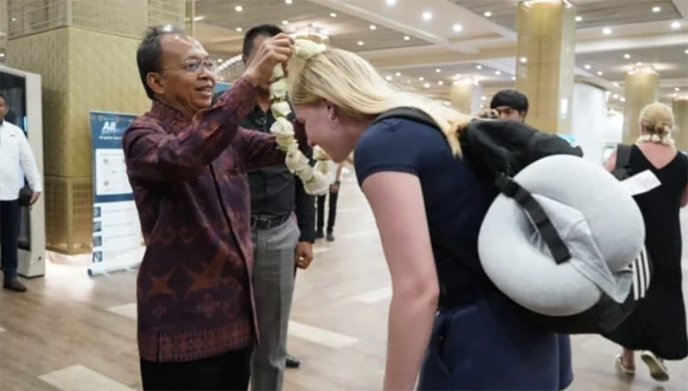 Gubernur Bali Wayan Koster menyambut wisatawan mancanegara dengan pengalungan bunga setibanya di Bandara I Gusti Ngurah Rai, Minggu (28/12/2025)