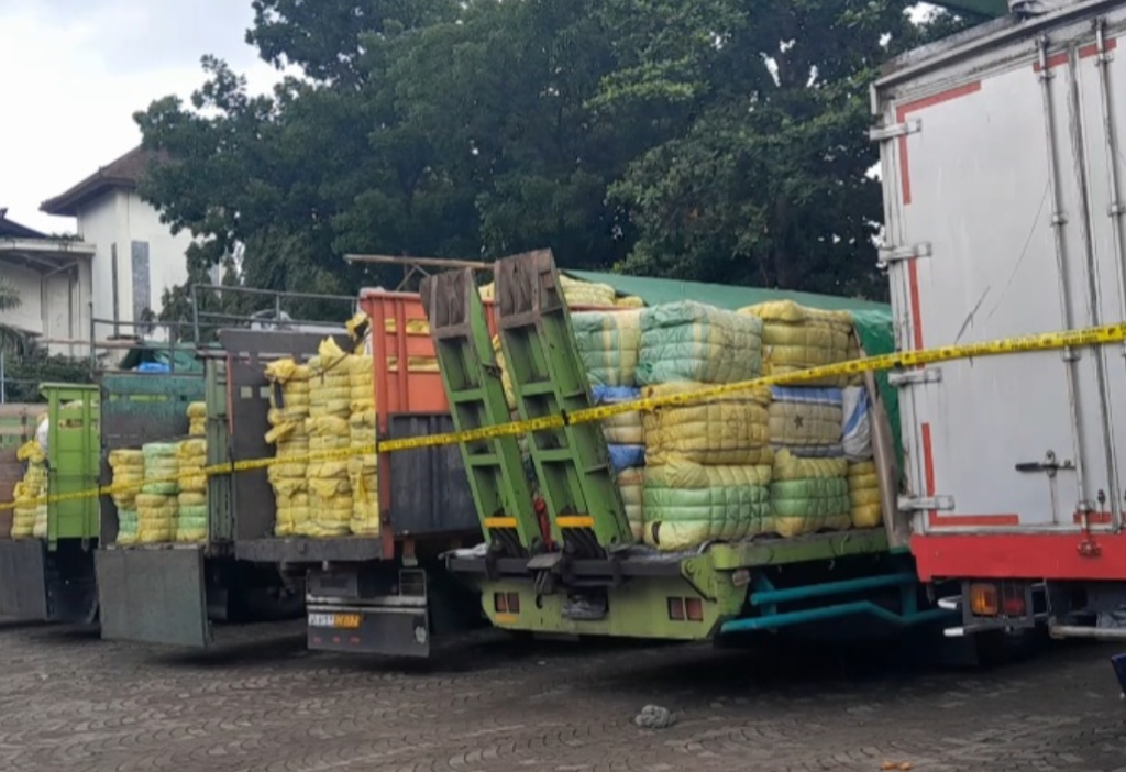 Petugas Satgas Gakum Importasi Ilegal Dittipideksus Bareskrim Polri mengamankan ratusan bal pakaian bekas impor ilegal yang dimuat dalam sejumlah truk saat pengungkapan kasus jaringan impor pakaian bekas asal Korea Selatan di Bali, Senin (15/12/2025).