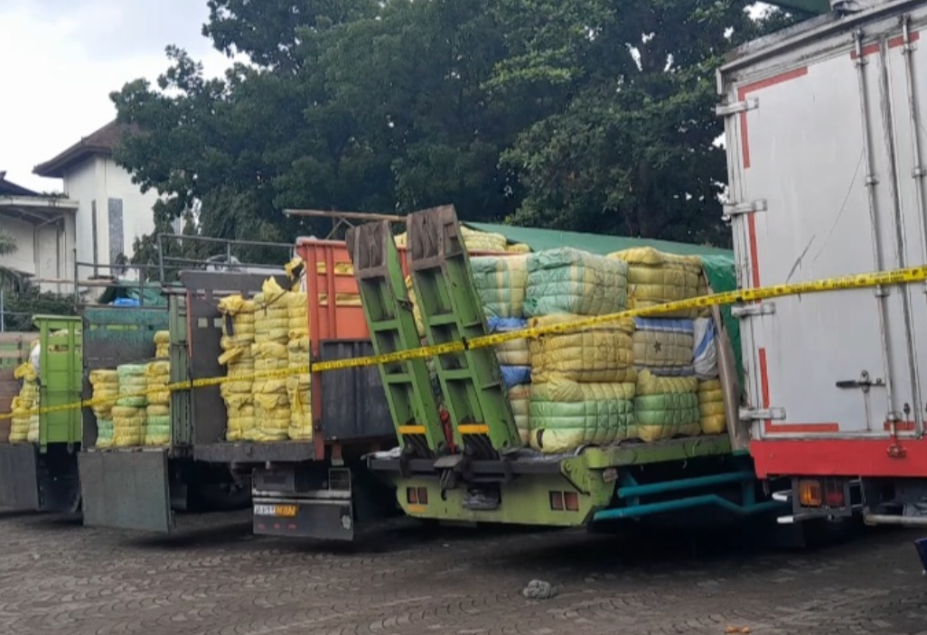 Petugas Satgas Gakum Importasi Ilegal Dittipideksus Bareskrim Polri mengamankan ratusan bal pakaian bekas impor ilegal yang dimuat dalam sejumlah truk saat pengungkapan kasus jaringan impor pakaian bekas asal Korea Selatan di Bali, Senin (15/12/2025).