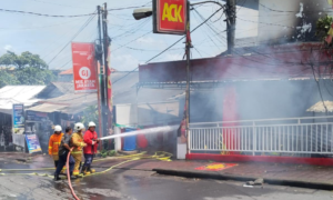 Petugas pemadam kebakaran berupaya memadamkan api yang melahap outlet ACK Bualu di Jalan Kurusetra, Kelurahan Benoa, Kuta Selatan, Selasa (20/1/2026).