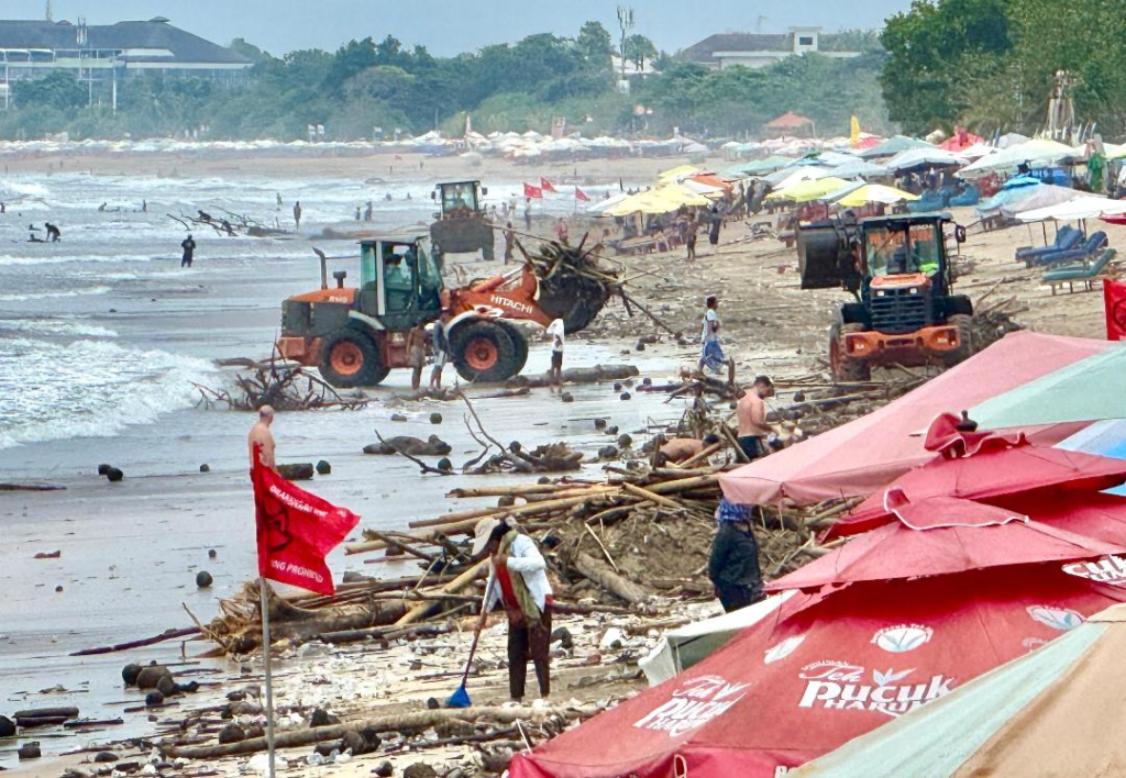 Petugas kebersihan bersama alat berat membersihkan tumpukan sampah kiriman yang menutupi kawasan Pantai Kuta, Badung.