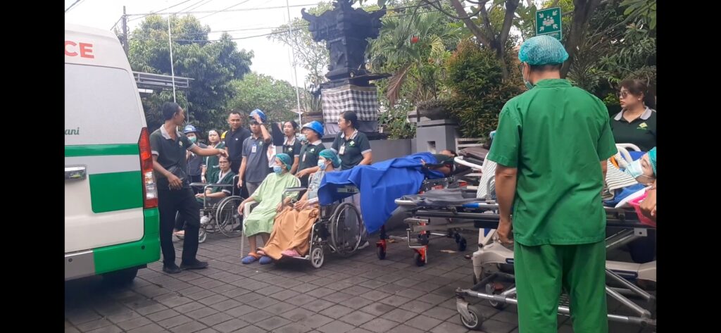 Simulasi kebakaran dan evakuasi di RSU Bhakti Rahayu Denpasar, Sabtu (28/2/2026). Petugas mengevakuasi pasien menggunakan kursi roda dan brankar menuju titik kumpul sesuai prosedur Code Red, sekaligus melatih kesiapsiagaan menghadapi kondisi darurat.