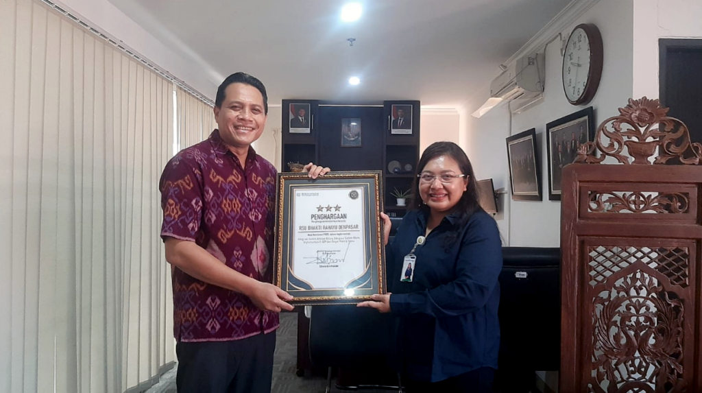Kepala Kantor Cabang BPJS Kesehatan Denpasar, dr. Nyoman Wiwiek Yulia Dewi (kanan), menyerahkan piagam penghargaan bintang tiga implementasi antrean online MJKN kepada Direktur RSU Bhakti Rahayu Denpasar, Jumat (6/2), di Kantor BPJS Kesehatan Denpasar.