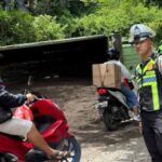 Petugas kepolisian melakukan pengaturan arus lalu lintas di sekitar lokasi truk bermuatan pasir yang terguling di tanjakan kawasan Goa Gong, Ungasan, Selasa (17/2/2026).