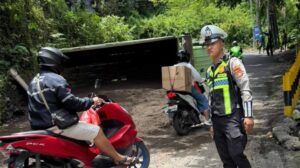 Petugas kepolisian melakukan pengaturan arus lalu lintas di sekitar lokasi truk bermuatan pasir yang terguling di tanjakan kawasan Goa Gong, Ungasan, Selasa (17/2/2026).