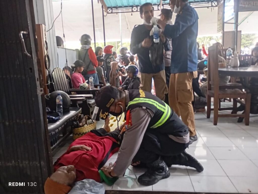 Seorang petugas kepolisian memberikan pertolongan pertama kepada pemudik yang pingsan akibat kelelahan saat antre menyeberang di kawasan Pelabuhan Gilimanuk, Jembrana, Bali, Minggu (15/3/2026).