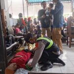 Seorang petugas kepolisian memberikan pertolongan pertama kepada pemudik yang pingsan akibat kelelahan saat antre menyeberang di kawasan Pelabuhan Gilimanuk, Jembrana, Bali, Minggu (15/3/2026).