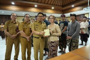 Bupati Adi Arnawa saat menyerahkan buku rekening tabungan kepada 26 Sekaa dan Komunitas Seni yang akan menjadi Duta Kabupaten Badung pada PKB XLVIII Tahun 2026, di Puspem Badung, Senin (13/4).